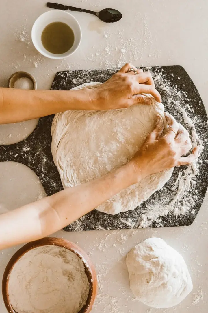 Hands kneading dough on a floured surface