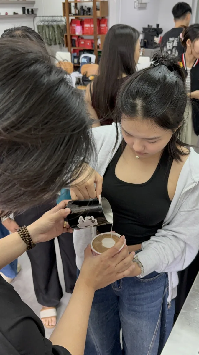 Student practising milk pouring with instructor guidance